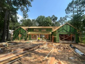 Wood-framed home under construction with green sheathing among trees