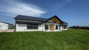Finished white farmhouse-style custom home with a black roof and green lawn