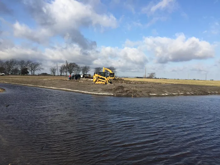 Bulldozer grading land beside a pond